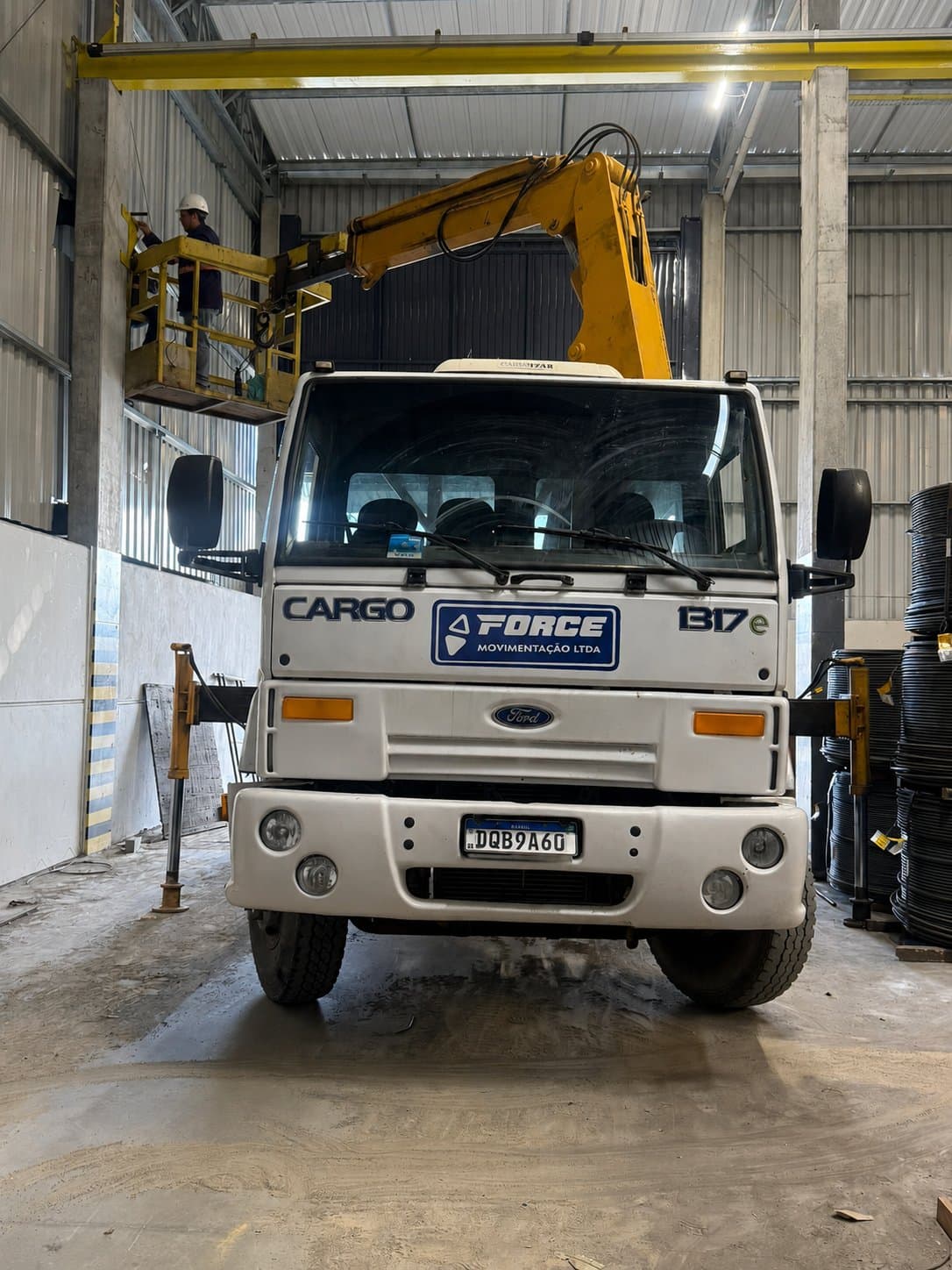 Equipe própria da Force Movimentação instalando equipamento em plataforma elevatória, com caminhão munck da empresa