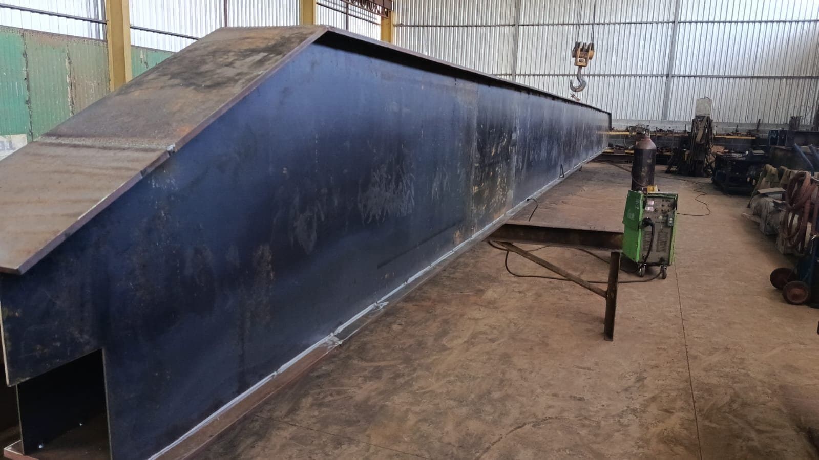 Viga de ponte rolante em fabricação, com pontos de solda e talha suspensa, na Force Movimentação